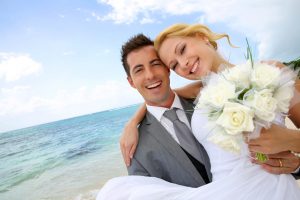 Groom holding bride in his arms at the beach