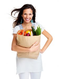 Happy young woman carrying a shopping bag full of groceries