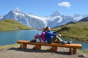 Travelers on a bench enjoying Alpine panorama