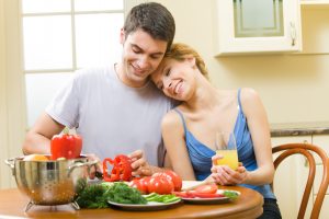 Young happy couple making salad at home together
